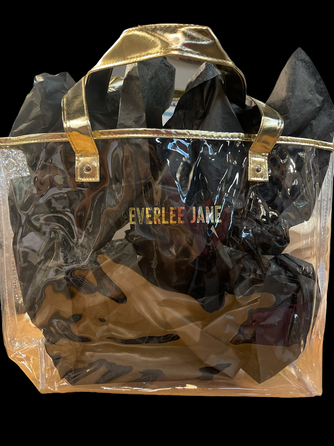 Clear waterproof tote bag with gold handles, trim, black tissue, and "EVERLEE JANE" in gold. Available in S, M, L.