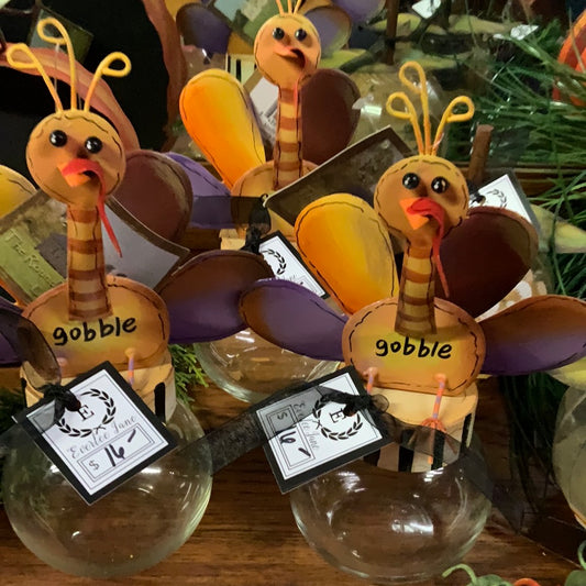 Turkey Topper Glass Bowls with cartoon turkey faces, paper feathers, "gobble" text. Priced at $14. Sizes: small, medium, large.