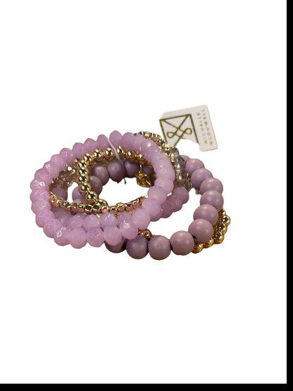 Three blush beaded Mandy Bracelets with gold accents and a white tag with gold logo. Available in S, M, L.