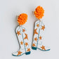 Orange beaded studs with dangling white cowboy boots, orange stars, blue accents. Sizes available: one size fits all.