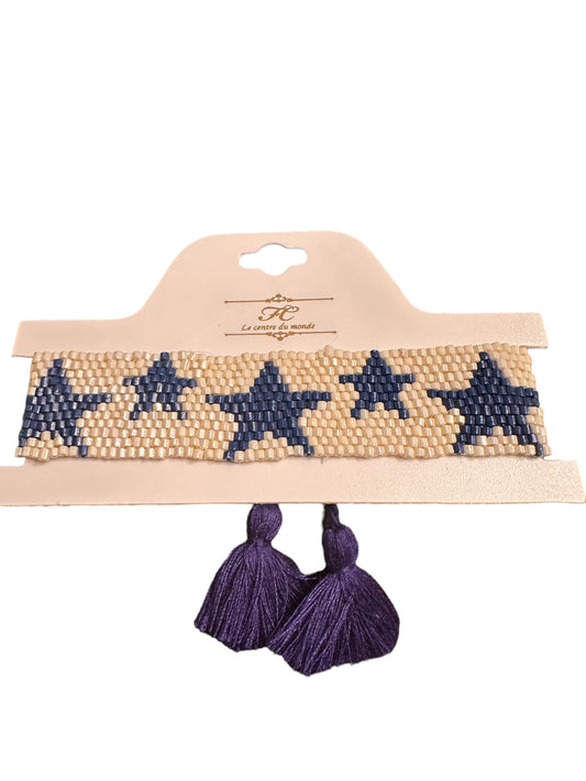Beaded bracelet with blue star patterns on cream, finished with two purple tassels. Sizes available: S, M, L.