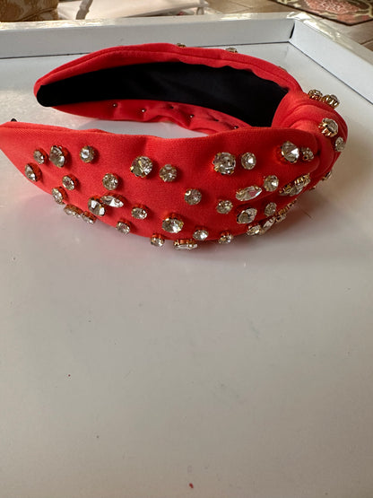 Red knotted headband with large rhinestones, shiny finish, black lining. Sizes: S, M, L.