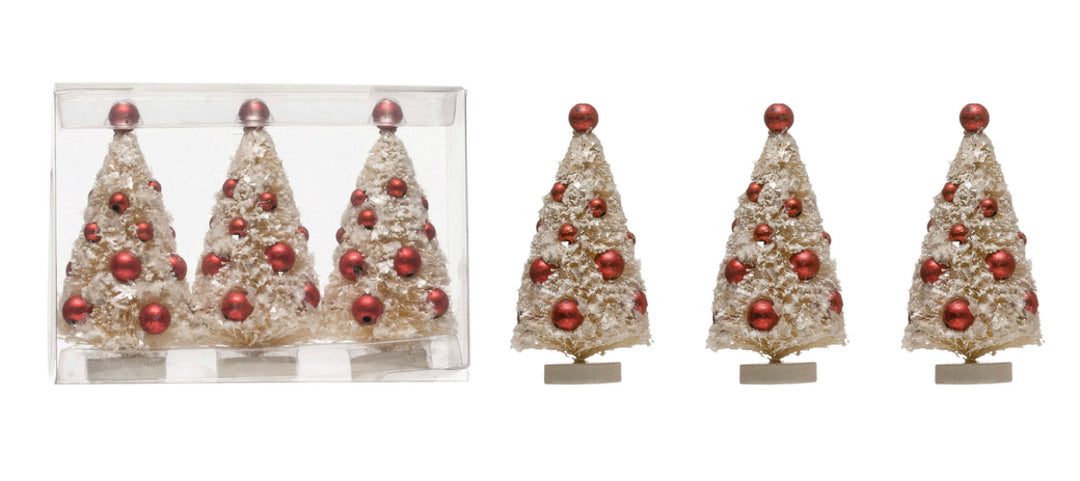 Three snow-flocked bottle brush Christmas tree ornaments decorated with small red ornaments.